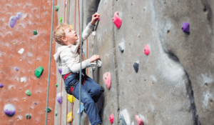 Young boy climbing to wall with ropes.
