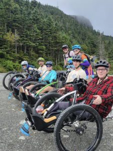 Adaptive riders and volunteers pose at the top of the course.