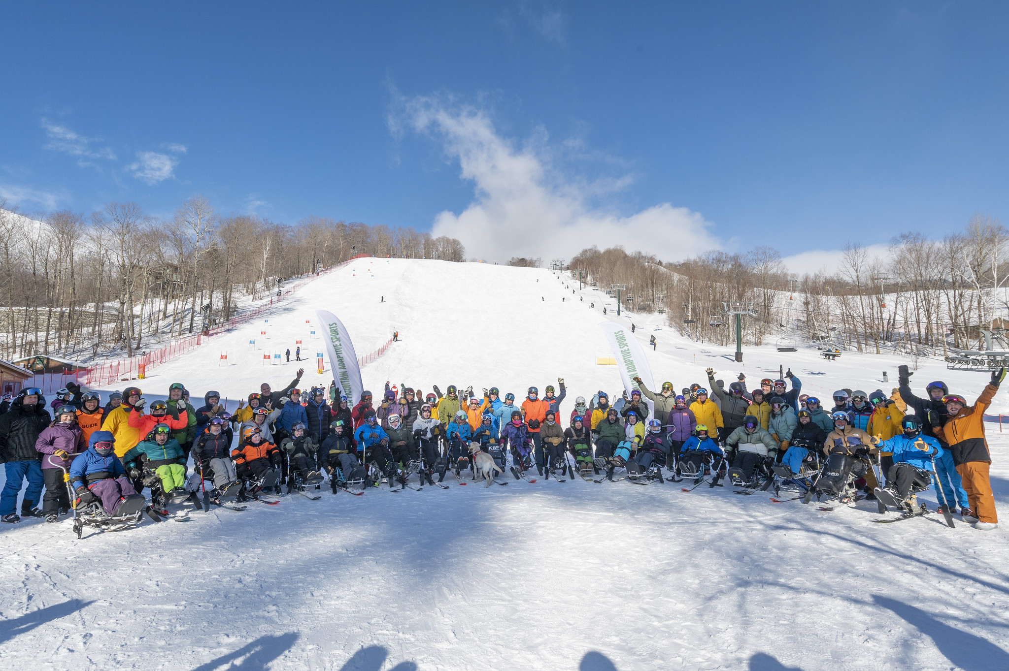 24 monoskiers and volunteers pose in the group photo of the 2024 Stowe Monoski Camp.