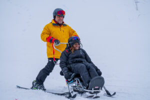 A veteran enjoys skiing in a bi-ski with an instructor from Spaulding Adaptive Sports Centers.