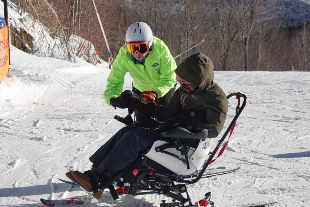 Allie Peterson leads a lesson with an athlete in the TetraSki at the Stowe Monoski Camp.