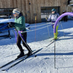 A visually impaired skier is lead by her coach.