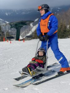 Ski instructor with small kid in a bi-ski