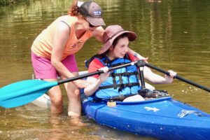 Young kayaker getting situated with her coach