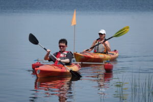 An athlete enjoying adaptive kayaking on the calm water.